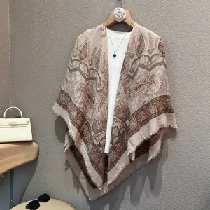 Detail view of the beige paisley print shawl scarf with fringe hem, elegant styling prop.