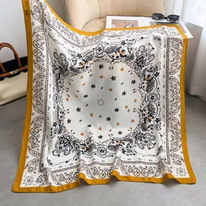 Nahaufnahme des eleganten Seiden-Quadratschals mit Paisley-Muster und auffälligem gelben Rand.