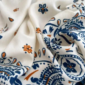 Detailaufnahme eines weißen Seidenschals mit blauem und orangenem Paisley-Blumenmuster.