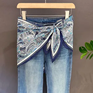 Blue denim jeans with paisley silk scarf tied at waist, chic multi-way styling detail shot.