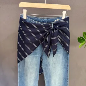 Detail view of denim jeans featuring a chic navy striped waist scarf wrap for trendy layers.