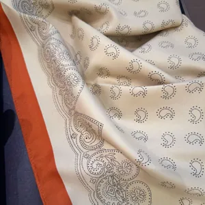 Close-up view of the elegant paisley patterned silk scarf featuring a vibrant orange border.