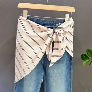 Denim jeans with stylish striped waist scarf wrap, trendy layered clothing accessory for women.