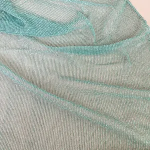 Detailed view of the shimmering pleated mint green scarf fabric texture close up.
