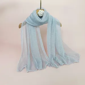 Detailed close-up of a light blue pleated metallic shawl hanging on a wooden hanger.