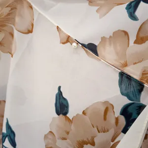 Close-up detail of floral print sun protection shawl fabric with elegant pearl button.