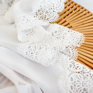 Close-up detail of white lace trim and chiffon fabric, soft and elegant texture display.