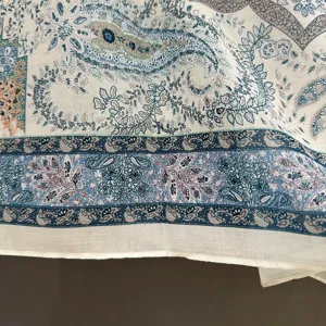 Detalle de bufanda con estampado paisley fina textura, elegante borde y suave caída fluida.