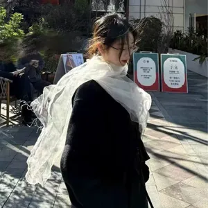Detail shot of white sheer mesh tassel shawl, elegant spring summer accessory for women travel.
