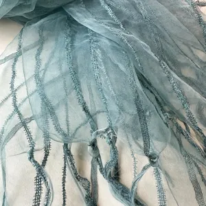Close-up of lightweight blue organza scarf texture, showing delicate vertical stripes and fringes.