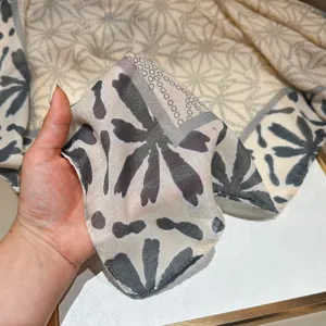 Detail shot showing the soft texture and abstract grey floral print of the lightweight scarf.