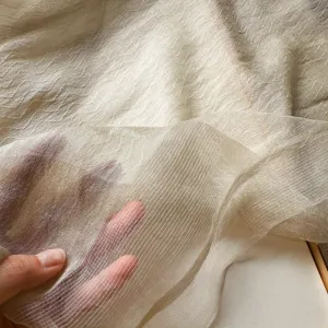 Detailaufnahme der feinen, transparenten Textur eines leichten Wolle-Seide-Mischgewebe-Schals.