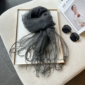 Close-up of dark grey sheer organza scarf detail showing crinkled texture and delicate fringes.