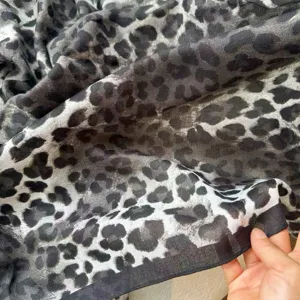 Close-up view of a soft grey leopard print scarf, showcasing lightweight fabric texture and drape.