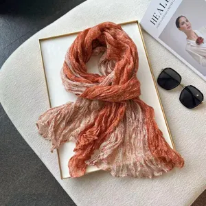 Detail shot of a stylish pleated paisley patchwork linen scarf in orange and white tones.