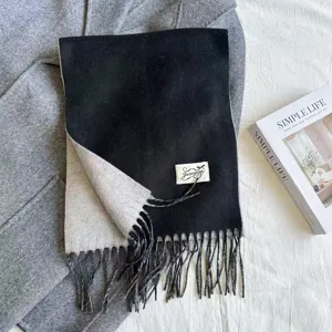 Detailed shot of the black and white faux cashmere scarf with elegant tassels and woven label.