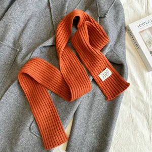 Knitted narrow scarf detail showing rib texture and stylish autumn winter everyday wear.