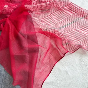 Gros plan détaillé de l'écharpe en soie et laine à carreaux rouges avec une texture douce.