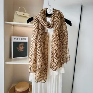 Detailansicht eines stilvollen braunen leichten Schals mit Zebramuster und weißem Kleid.