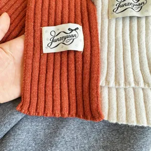 Ribbed knit scarf detail close up showing soft texture and brand label for autumn winter fashion.