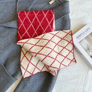 Detail view of the red and white diamond knitted cross scarf, cozy winter warm fashion accessory.