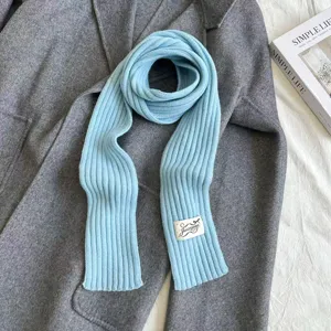 Detailed view of a light blue knitted ribbed scarf laid on a gray coat, perfect for autumn style.