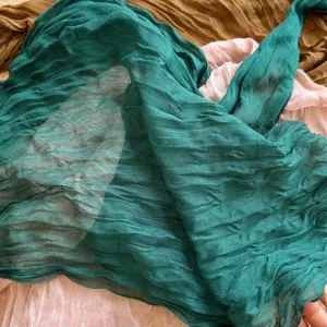 Details of pleated green scarf texture, soft cotton linen fabric, retro style drape accessory.