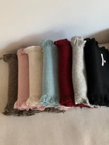 Detailed closeup view of rolled colorful knitted winter scarves with fine lace fringe details.