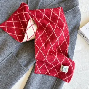 Detailed view of the cozy red and white diamond knitted scarf, soft winter texture and label.