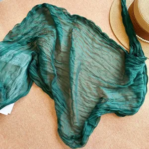 Detail shot of dark green crinkle scarf shawl, retro vintage style textured fabric accessory for women.