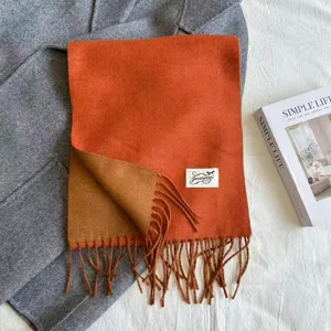 Close-up detail of reversible orange and brown fringe scarf with soft texture design.
