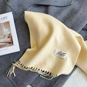 Cozy beige imitation cashmere scarf with fringe detail and label, elegant winter accessory.