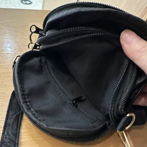 Black multi-zipper round crossbody bag inner pocket detail view showing compartments