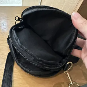 Black multi-compartment fabric shoulder bag interior detail showing metal zippers and lining.