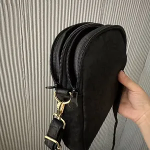 Detailed view of a black multi-compartment crossbody shoulder bag with metal hardware.