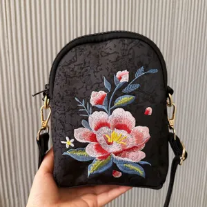 Detail view of black embroidered crossbody bag with floral design, ethnic style accessory.