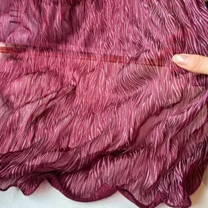 Detailed view of the pearlescent pleated burgundy scarf, showing soft fabric texture and weave.