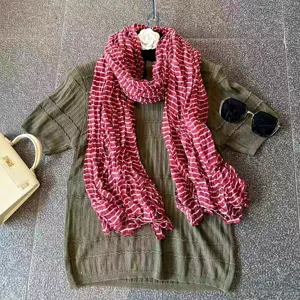 Detailed view of women's red and white striped crinkled long scarf, showcasing soft texture.