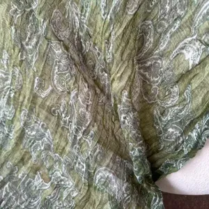 Olive green cotton linen paisley patterned scarf detail, retro literary soft warm shawl fabric texture.