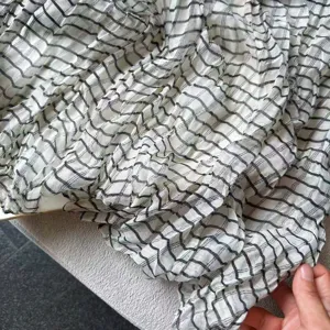 Detail view of women's pleated plaid long scarf, showcasing soft texture and chic stripe pattern.