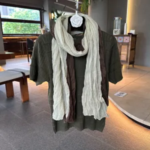 Chic women green knit short sleeve top combined with layered beige and brown scarves fashion.