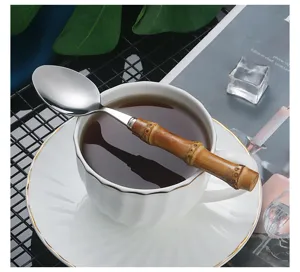 Stainless steel spoon with natural bamboo handle in cup detailed shot, elegant tableware design.