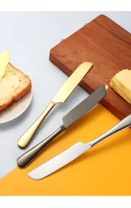 Stainless steel butter knife set detail showing gold black and silver knives on cutting board.