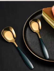 Stainless steel flat-headed dessert cake spoon detail with gold bowl and dark green handle.