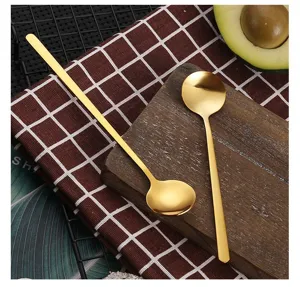Gold stainless steel long handled mixing spoon and round dessert spoon detail view.