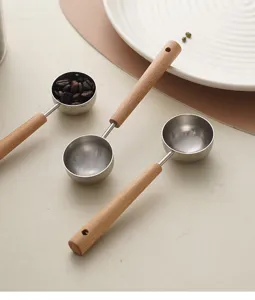 Stainless steel measuring spoon with wooden handle detail shot for kitchen coffee beans and tea.