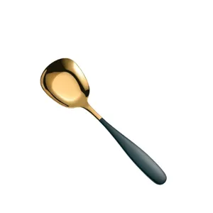 Stainless steel flat bottom spoon with gold head and dark green handle for modern table.