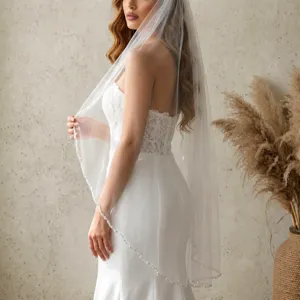 Dettaglio velo da sposa, tessuto in tulle trasparente con delicato bordo di perle cucite.