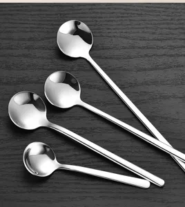 Close-up detail of stainless steel round spoons on dark wood, polished metal finish.