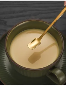 Close-up detail of luxury gold stainless steel long handle square head stirring coffee spoon.